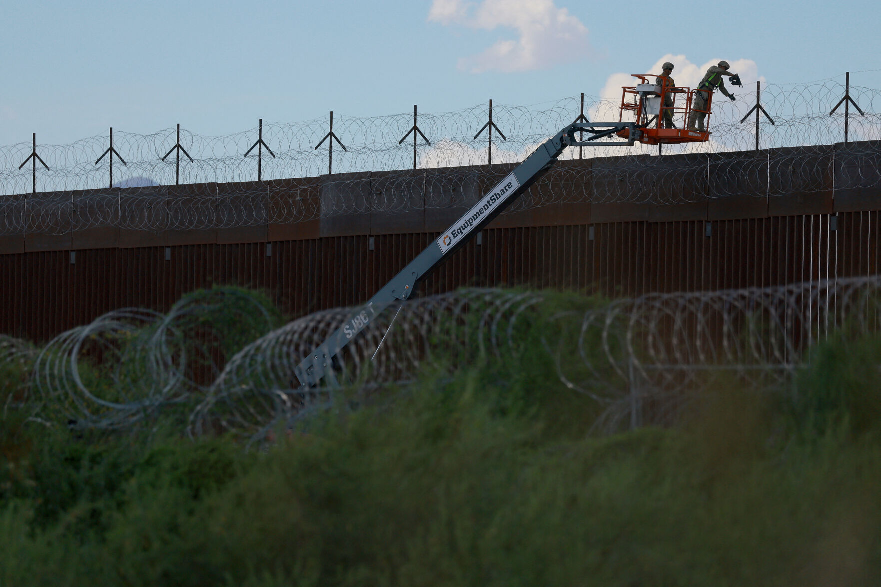A man is halted climbing the US-Mexico border wall. Under new Trump rules, US troops sound the alarm